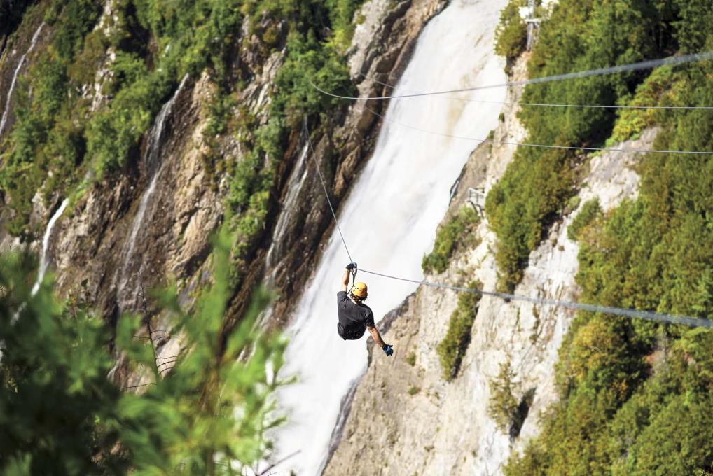 Un homme traverse l'anse de la chute en tyrolienne au Parc de la Chute Montmorency.