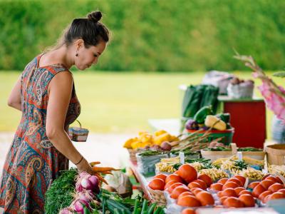 Un femme achète des fruits et des légumes frais dans un kiosque extérieur.