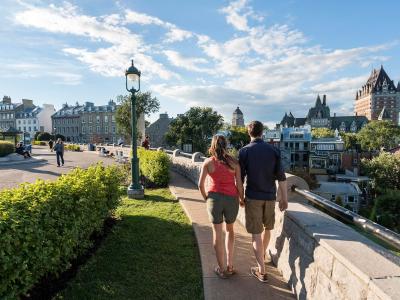Un couple marche sur la terrasse Pierre-Dugua-De Mons près de l'avenue Saint-Denis, en regardant le Château Frontenac.