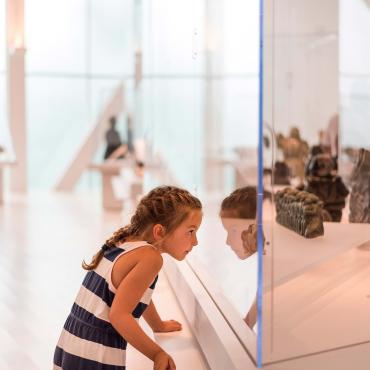Une fillette regarde à travers une vitrine dans une exposition au Musée national des beaux-arts du Québec.
