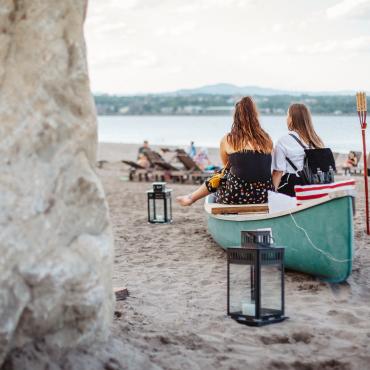 Two girls relax near a canoe on the beach at Baie de Beauport.